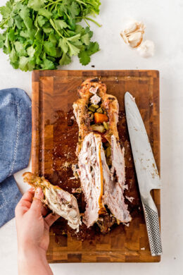 A turkey carcass on a wooden chopping board with the leg being removed.