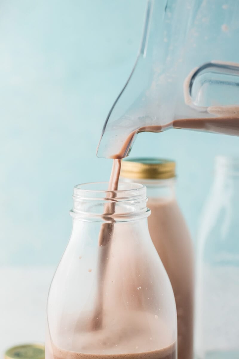 Pouring the chocolate coquito into a bottle.