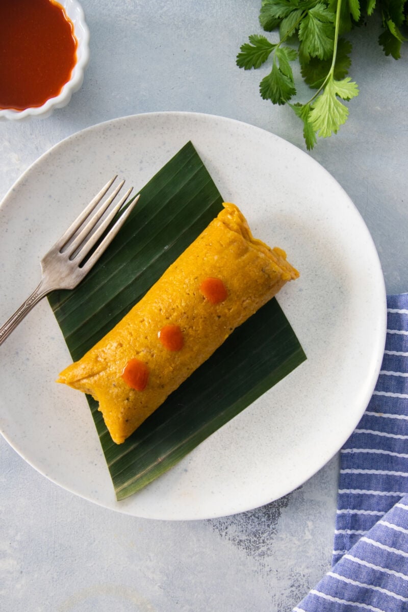 One overhead shot of a pastel en hoja topped with hot sauce