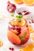 A glass of holiday sangria with orange and mint garnish.