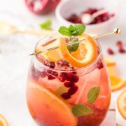 A glass of holiday sangria with orange and mint garnish.