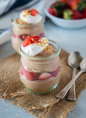 chocolate and strawberry cheesecake parfait topped with whipped cream and strawberries