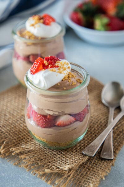 chocolate and strawberry cheesecake parfait topped with whipped cream and strawberries