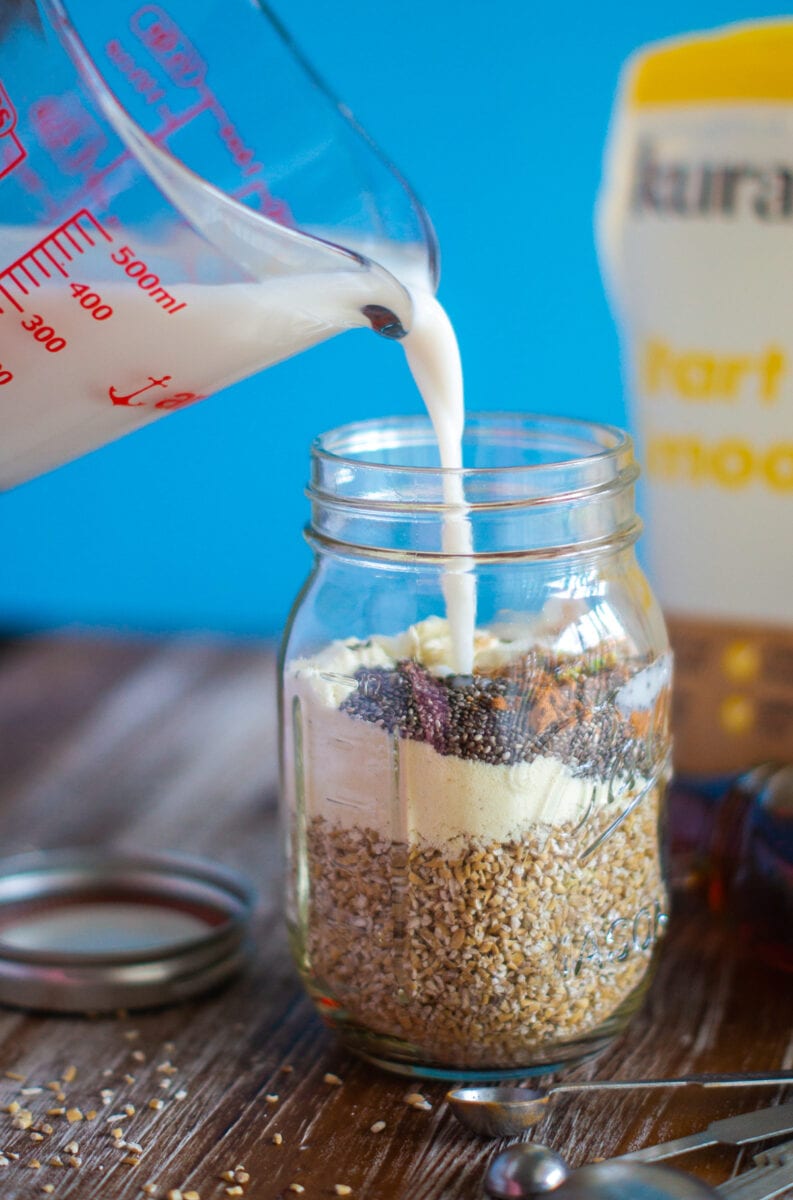 Milk being poured into the mason jar with dry ingredients.