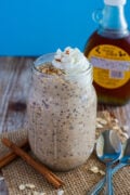 French Toast Overnight Oats served in a mason jar topped with whipped cream and a sprinkled of cinnamon.