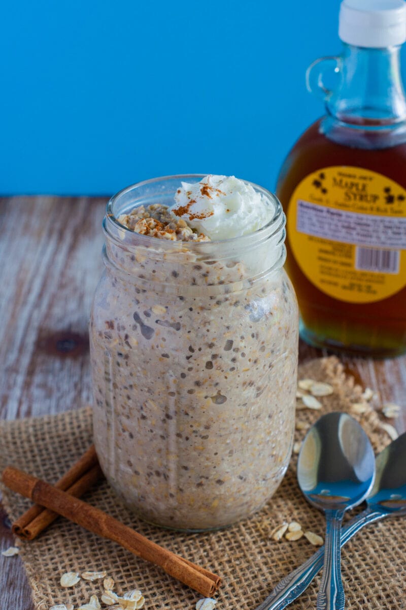 French Toast Overnight Oats served in a mason jar topped with whipped cream and a sprinkled of cinnamon.