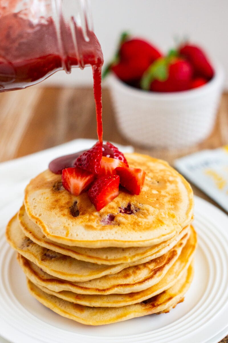 homemade strawberry sauce being poured over pancakes