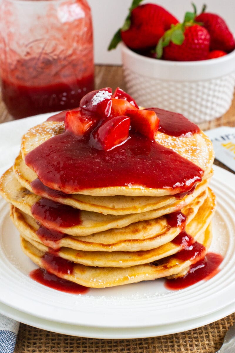 stacked pancakes topped with homemade strawberry sauce and fresh strawberries