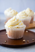 almond cupcakes with cream cheese frosting on a wooden plate sprinkled with chopped almonds