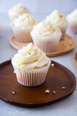 almond cupcakes with cream cheese frosting on a wooden plate ready to eat