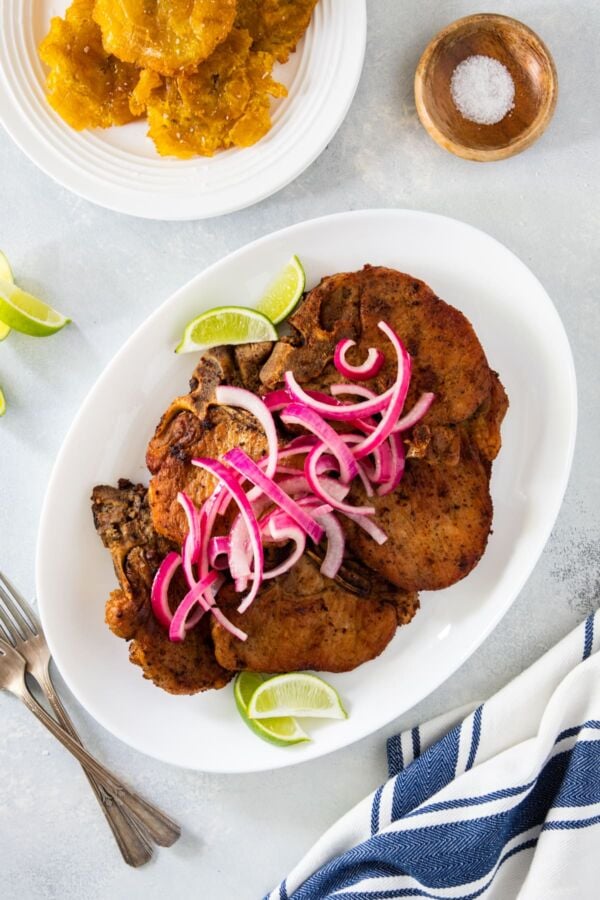 Fried pork chops piled on top of each other on a white serving plate.