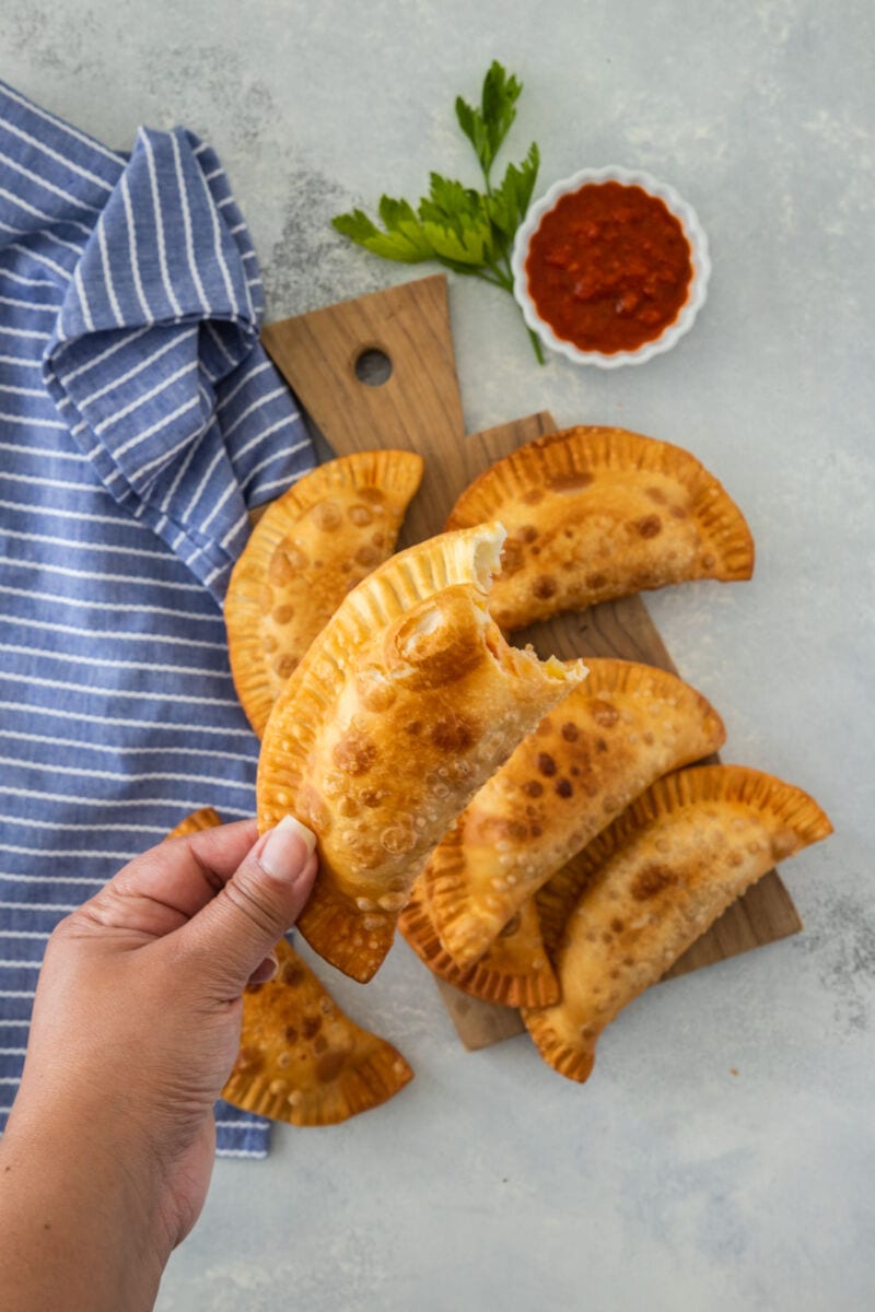 hand holding an empanada with a bite on it