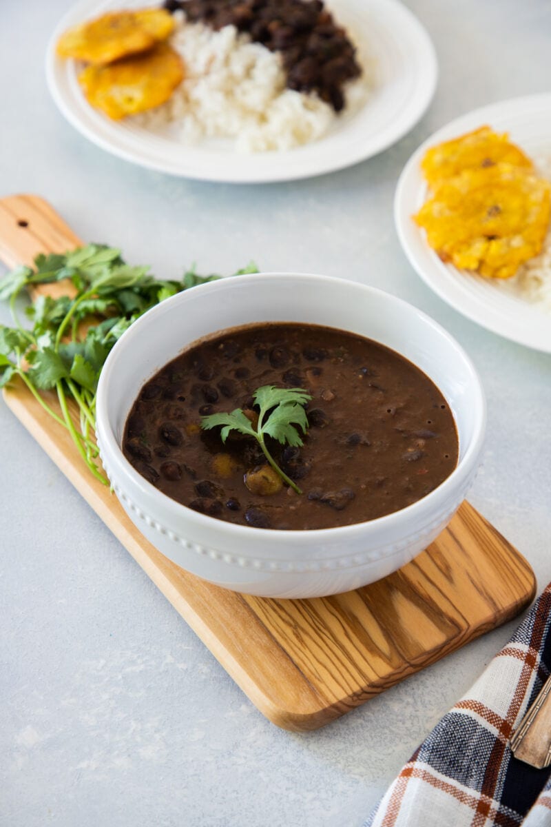 A white bowl with black bean stew garnished with fresh cilantro.