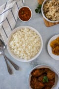 Overhead shot of a bowl of white rice next to sauces and stews.