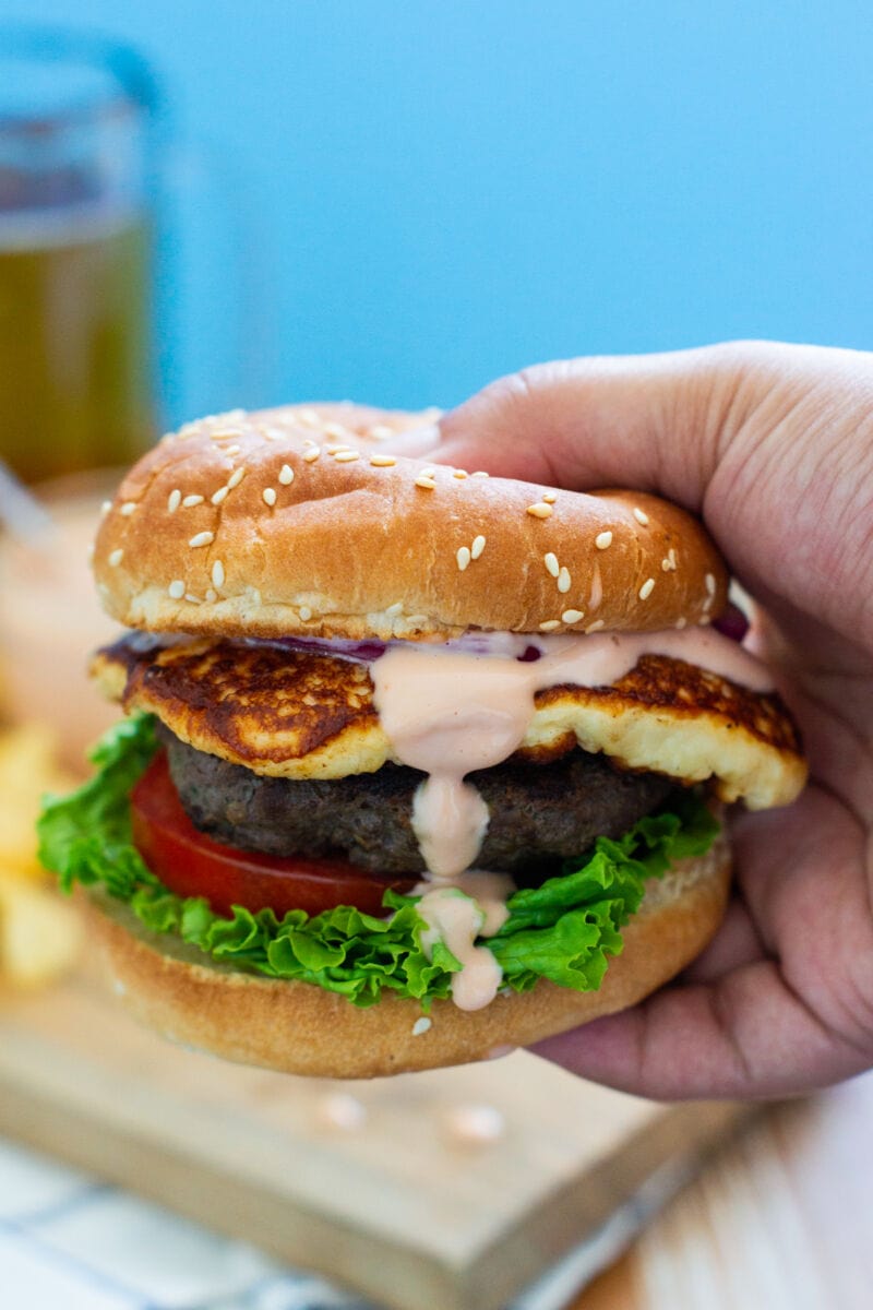 A hand holding a queso frito burger.