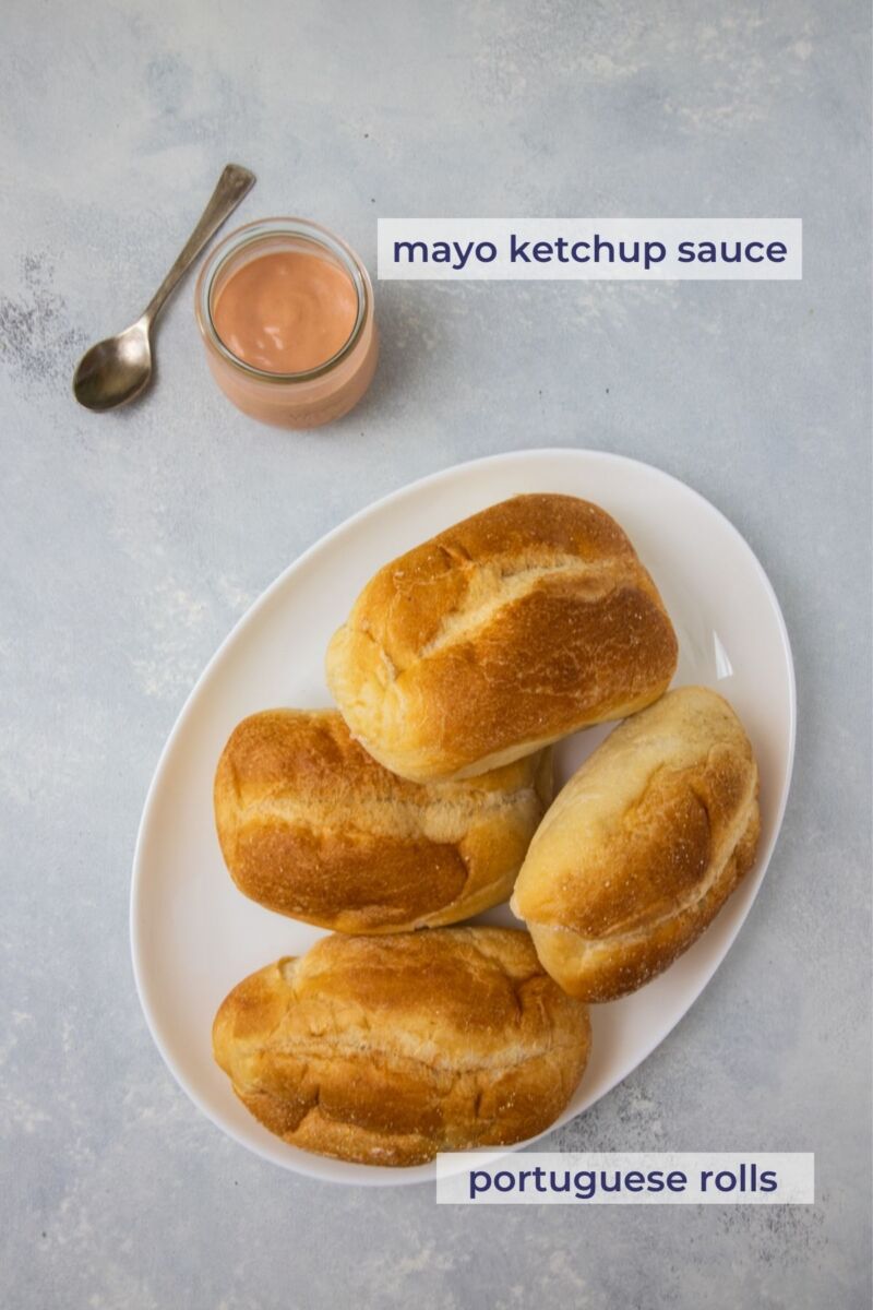 Four bread rolls on a plate next to a mayo-ketchup sauce.