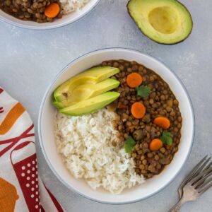 Lentil stew on a plate served with rice and avocado.