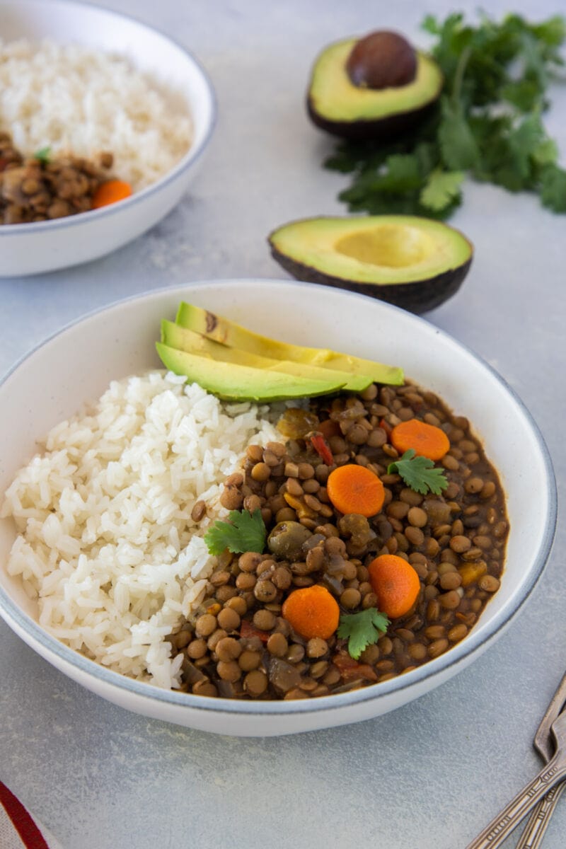 Lentil stew topped with sliced avocado and served with white rice.