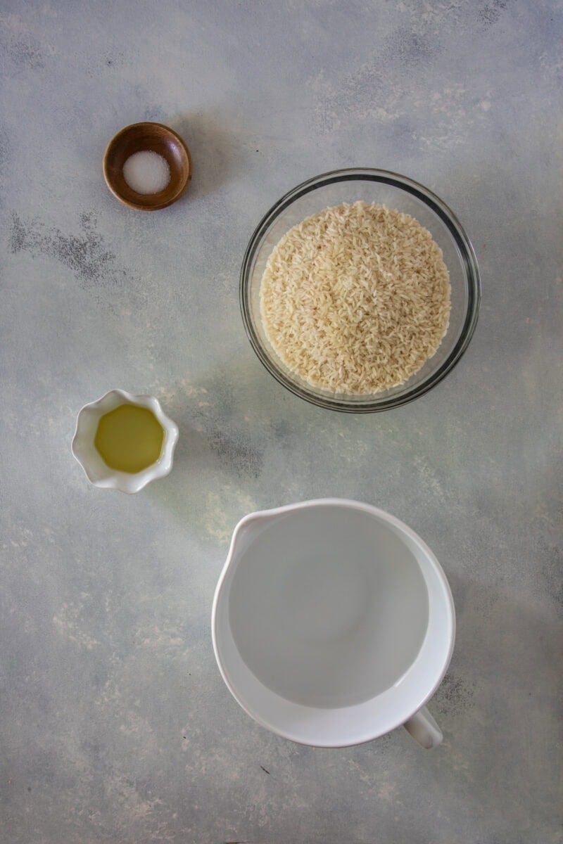 Uncooked white rice in a bowl with water, oil, and salt for cooking.