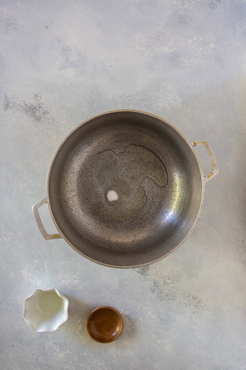 Oil and salt heating in a pot, top view before adding rice.