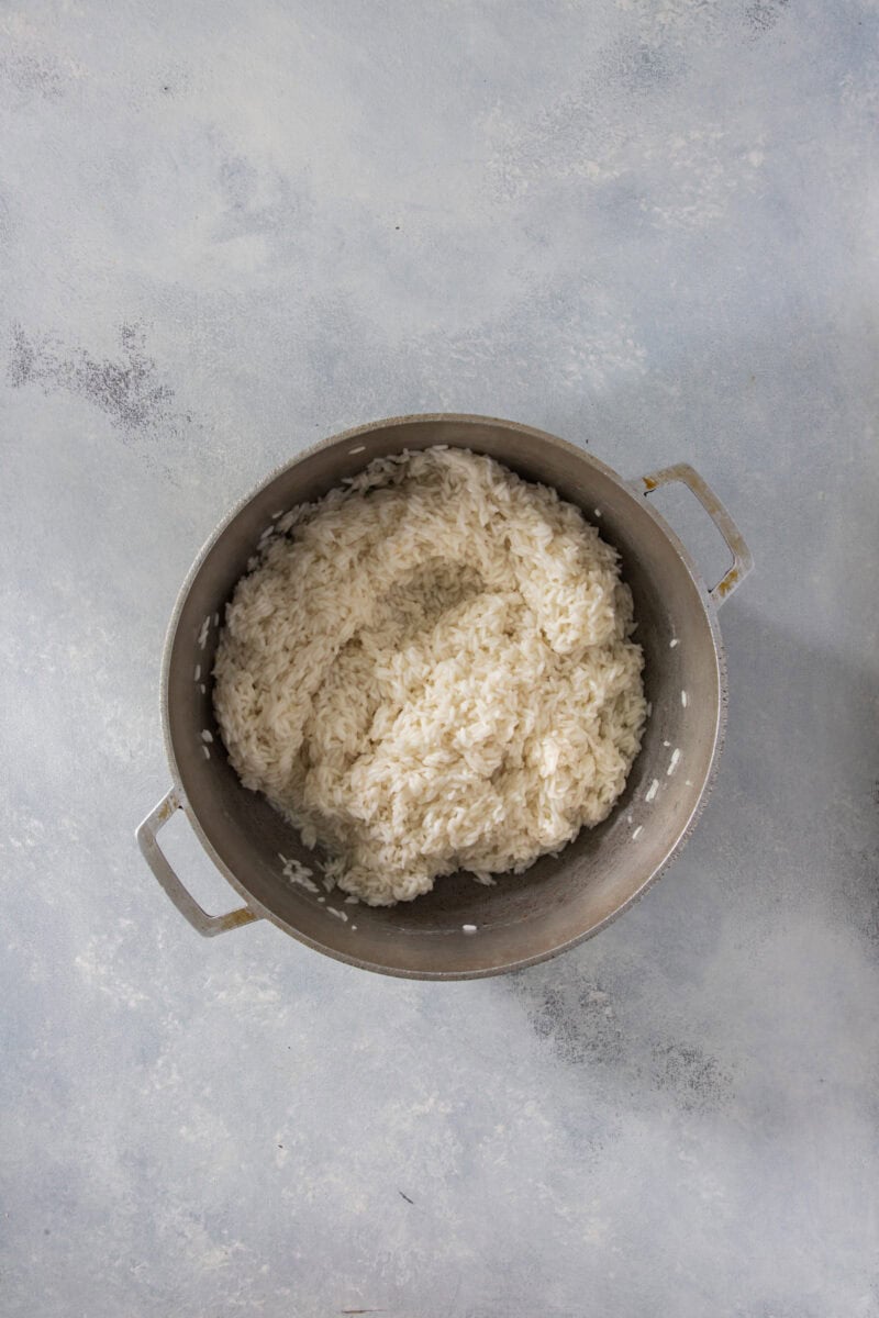 White rice cooking in a pot, partially absorbed water.