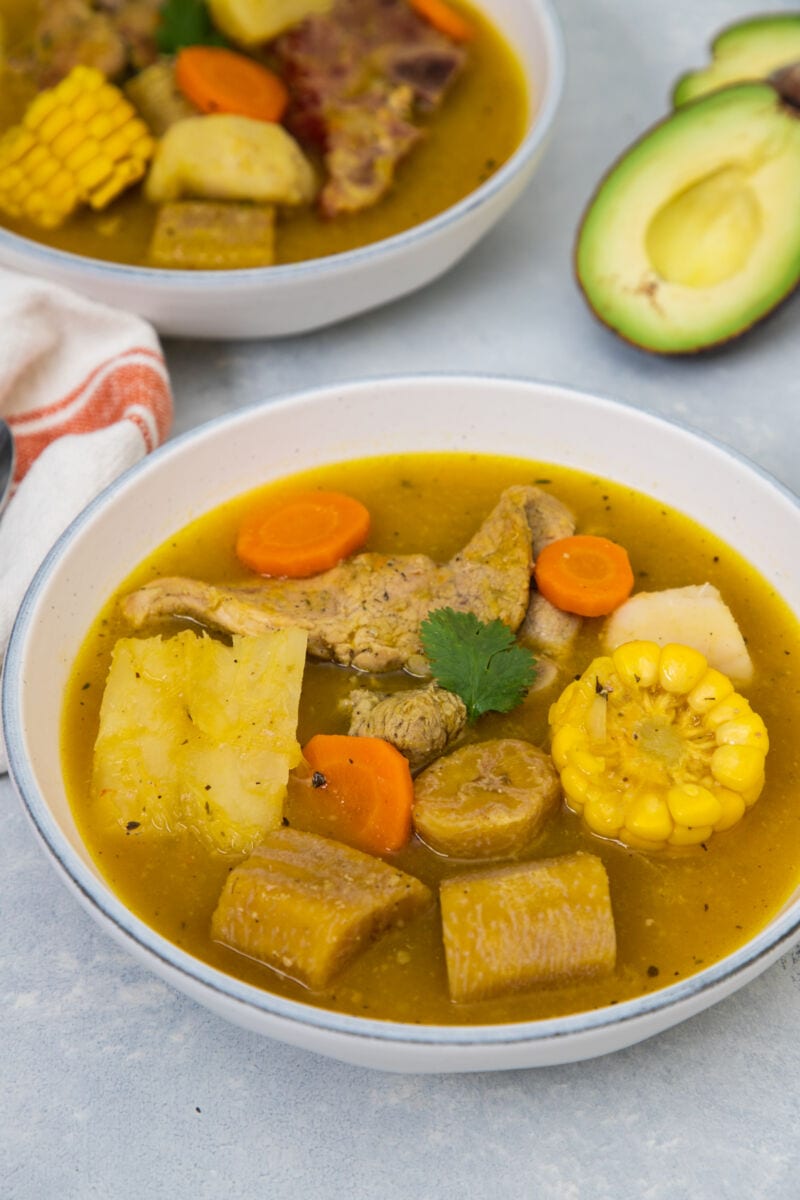 Two bowls of Sancocho with avocado on the side