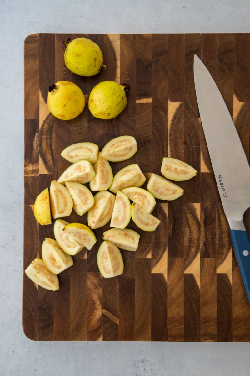 Guavas on a cutting board being cut into fourths