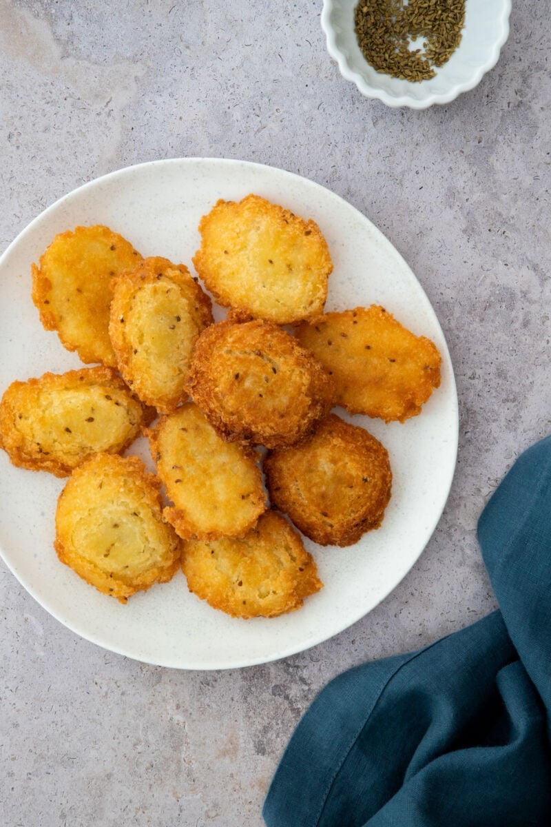 yuca fritters stacked on a white plate