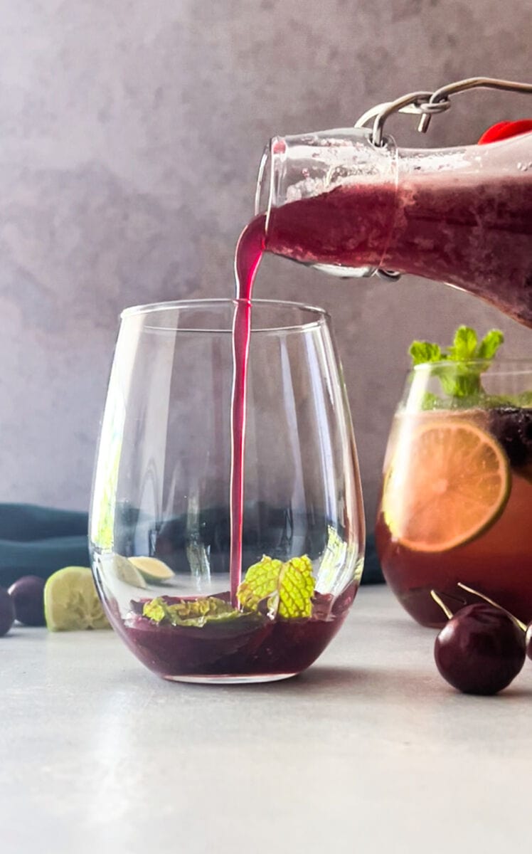 pouring cherry syrup into a glass for mojito