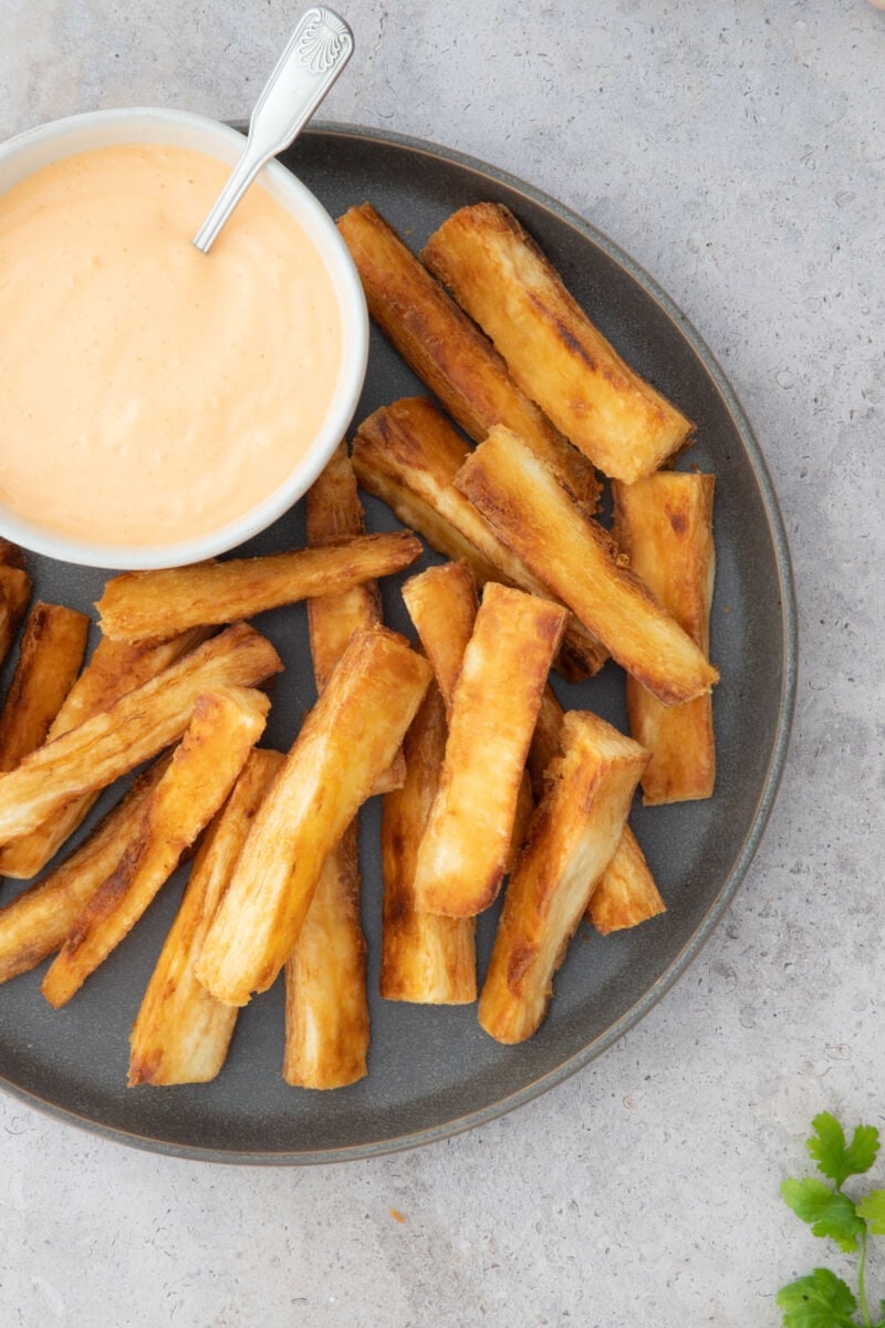 close up yuca fries in a gray plate with Sriracha Aioli on the side