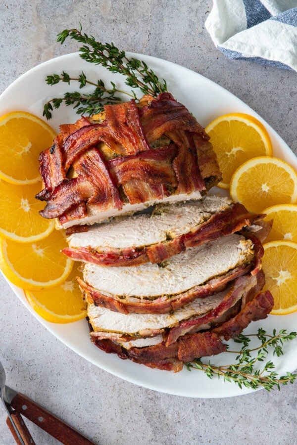 turkey breast wrapped in bacon on a platter sliced