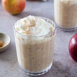 Apple pie smoothie served in a glass and topped with whipped cream