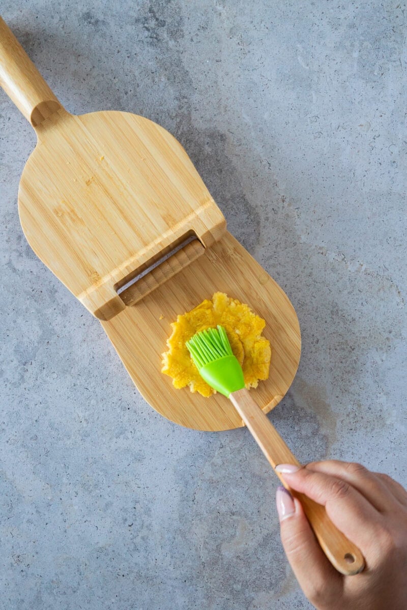 After the first fry, the plantain slices are gently pressed to create their classic shape. This step is key to achieving the perfect balance of a crispy exterior and a soft, tender interior that makes tostones so irresistible.