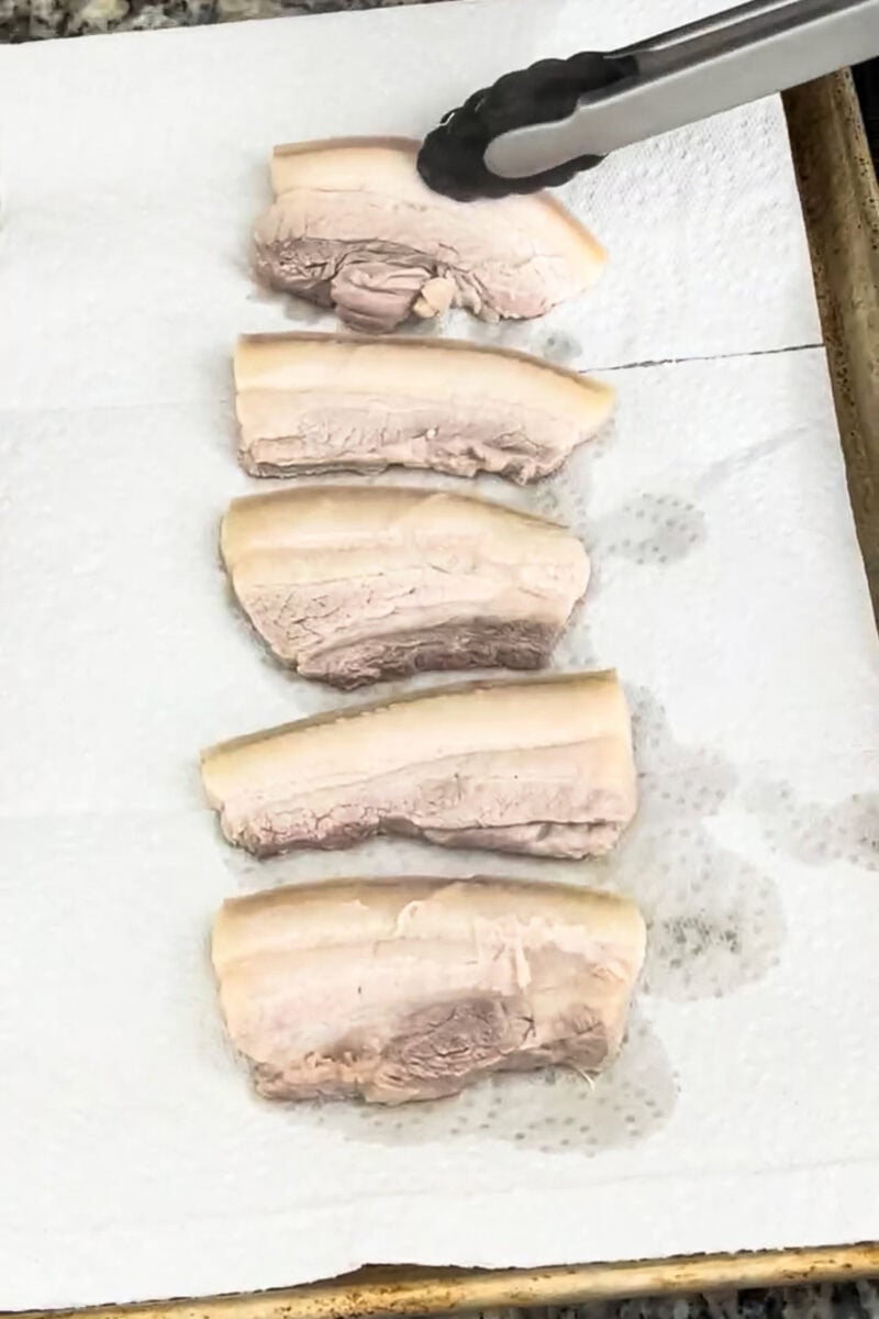 Boiled pork belly laid out on paper towels, drying for that perfect crispy chicharrón finish.