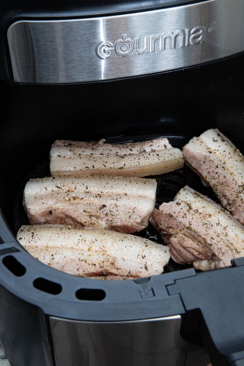 Seasoned pork belly placed in the air fryer, ready to crisp.