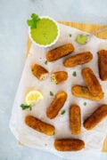Golden tuna and potato croquettes served on parchment with creamy cilantro dipping sauce and a lemon wedge.